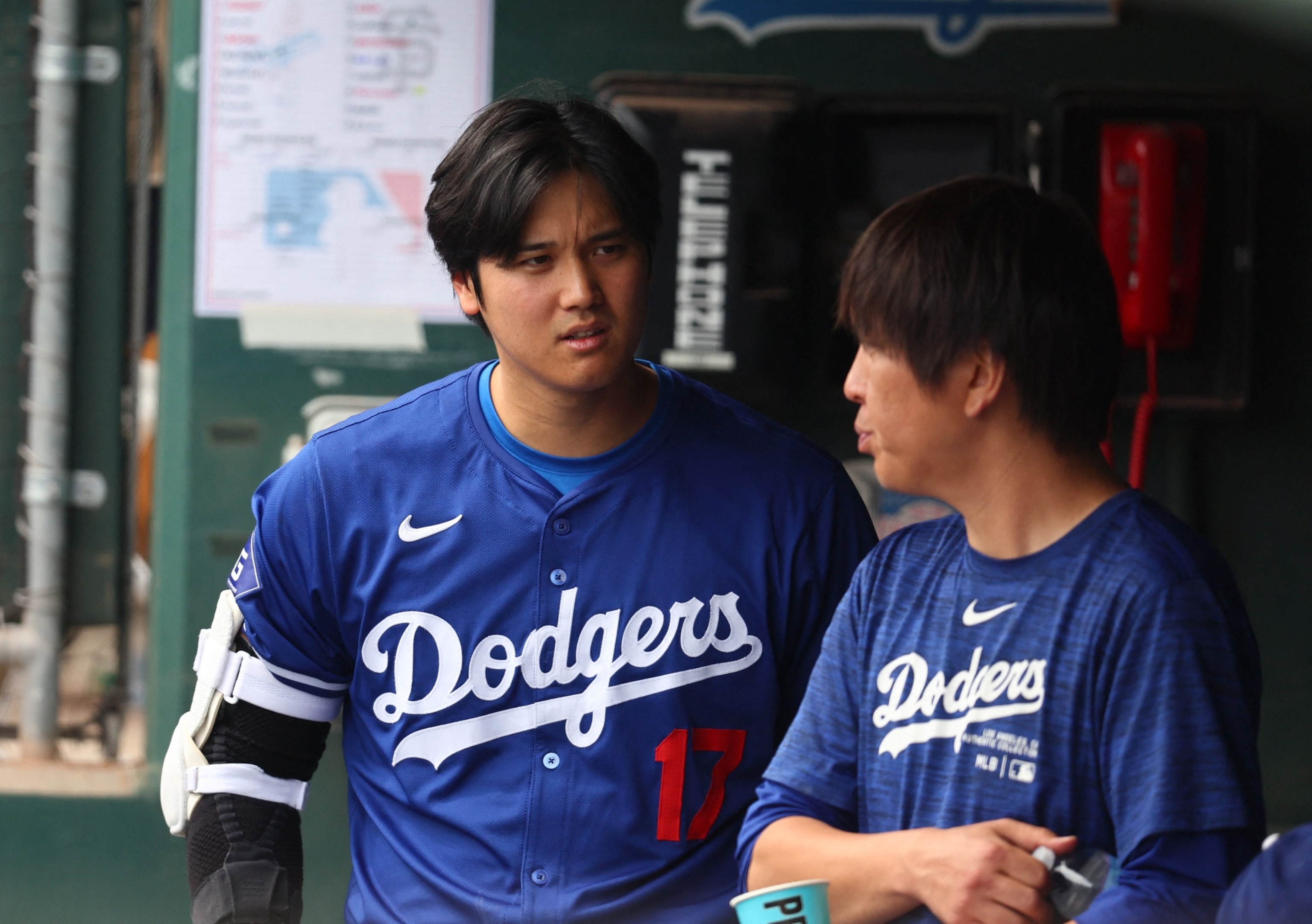PHOTO: Los Angeles Dodgers designated hitter Shohei Ohtani talks with translator Ippei Mizuhara in the dugout against the San Francisco Giants during a spring training baseball game in Phoenix, AZ, Mar. 12, 2024.