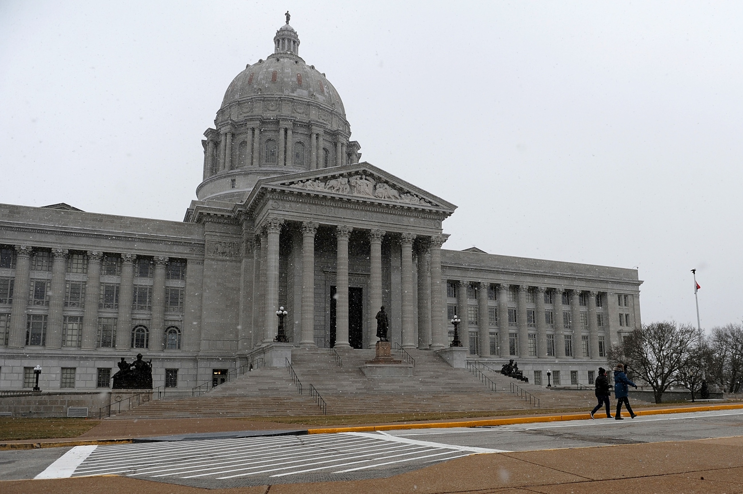 PHOTO: Pedestrians walk along as snow flurries fall outside the Missouri State Capitol Building on January 17, 2021 in Jefferson City, Missouri.