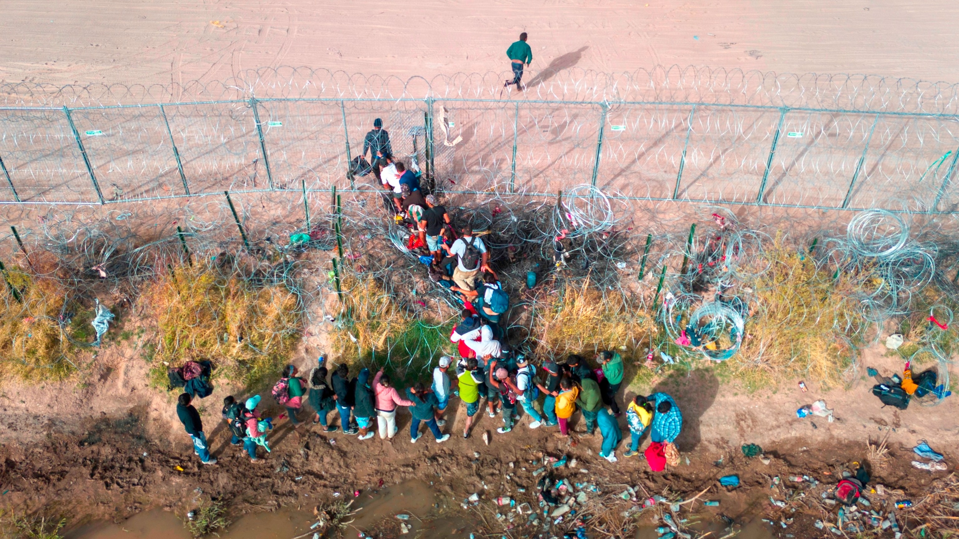 PHOTO: Immigrants pass through razor wire while crossing the U.S.-Mexico border on March 13, 2024, in El Paso, Texas. The wire was placed by the troops as part of Texas Gov. Greg Abbott's "Operation Lone Star" to deter migrants from crossing into Texas.