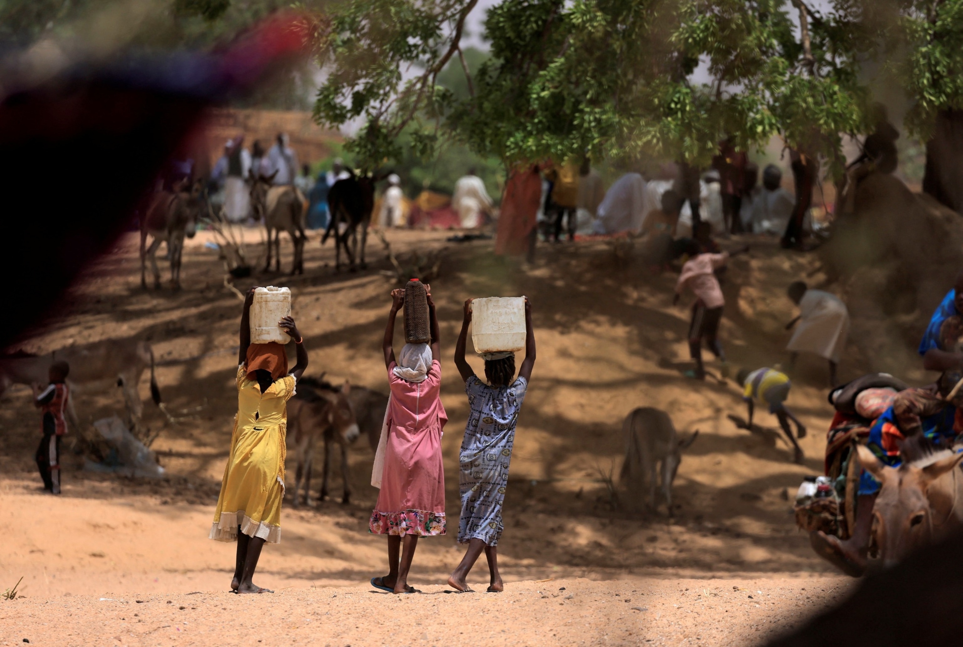 PHOTO: Sudanese women who fled the conflict in Sudan's Darfur region, and were previously internally displaced in Sudan, carry jerrycans of water, near the border between Sudan and Chad, while taking refuge in Borota, Chad, May 13, 2023. 