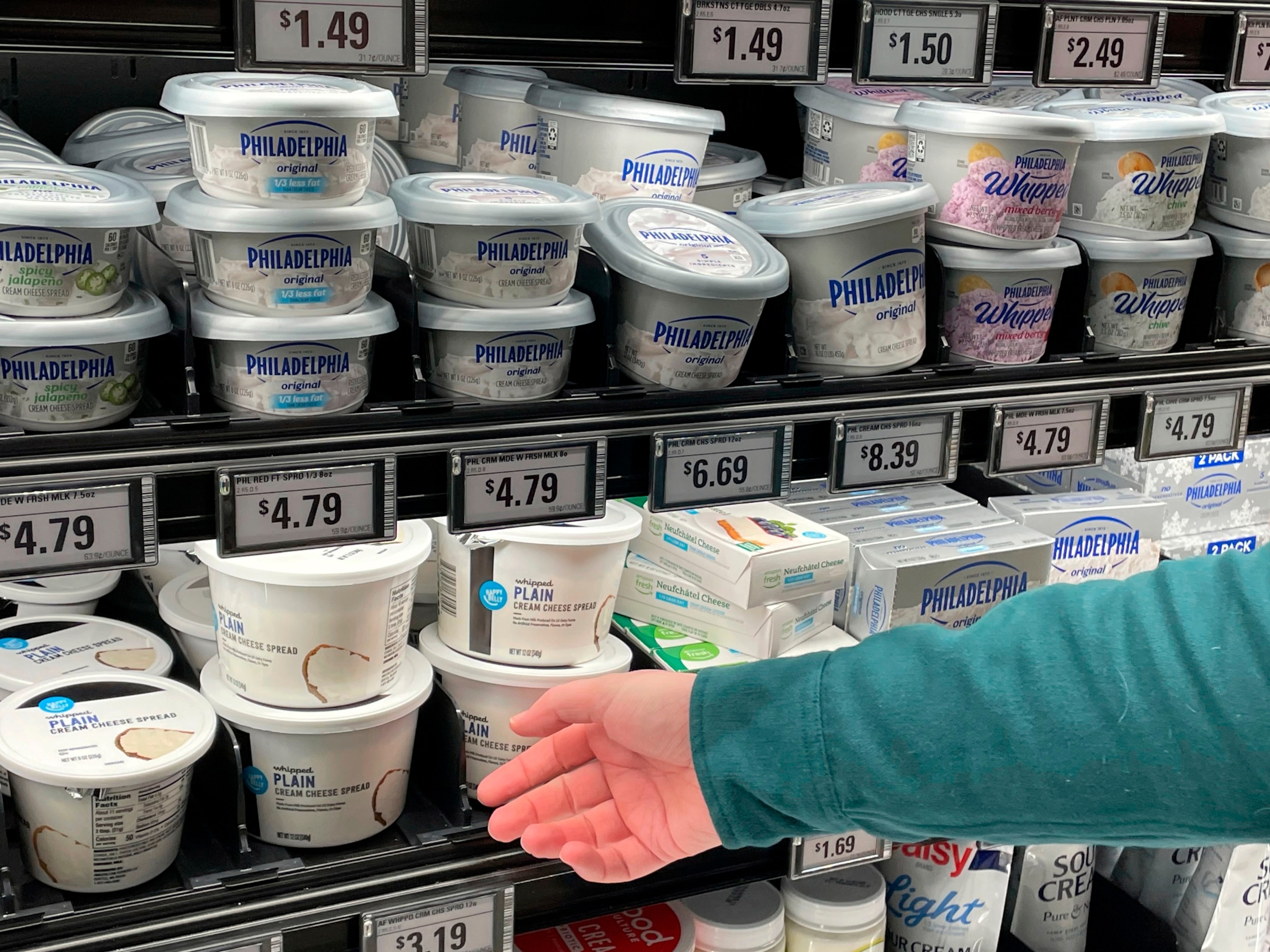 PHOTO: Stuart Dryden reaches for a store-label cream cheese at a grocery store , Feb. 21, 2024, in Arlington, Va.
