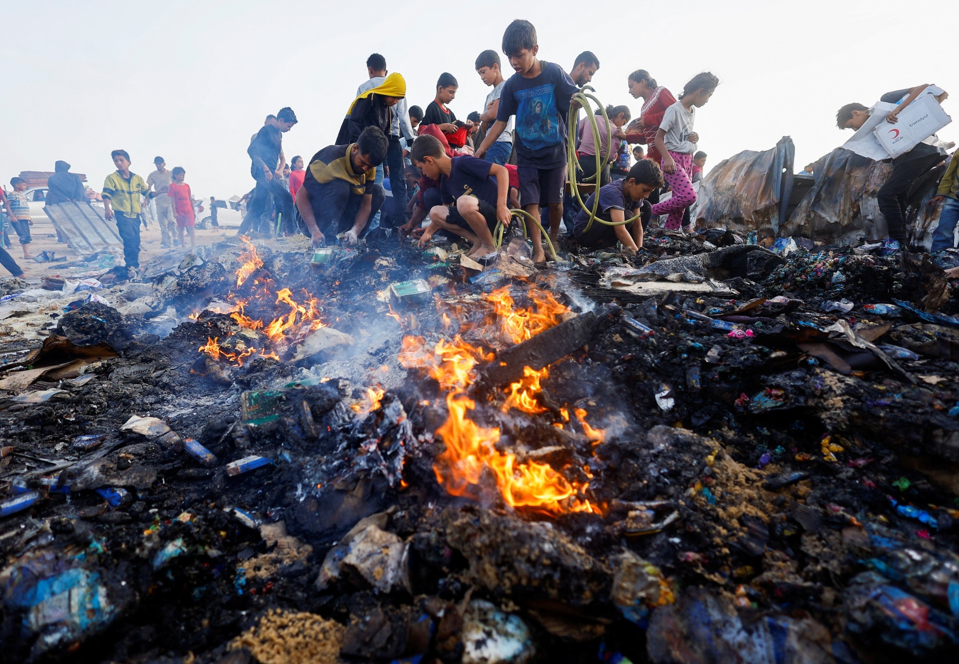 PHOTO: Palestinians search for food among burnt debris in the aftermath of an Israeli strike on an area designated for displaced people, in Rafah in the southern Gaza Strip, May 27, 2024. 