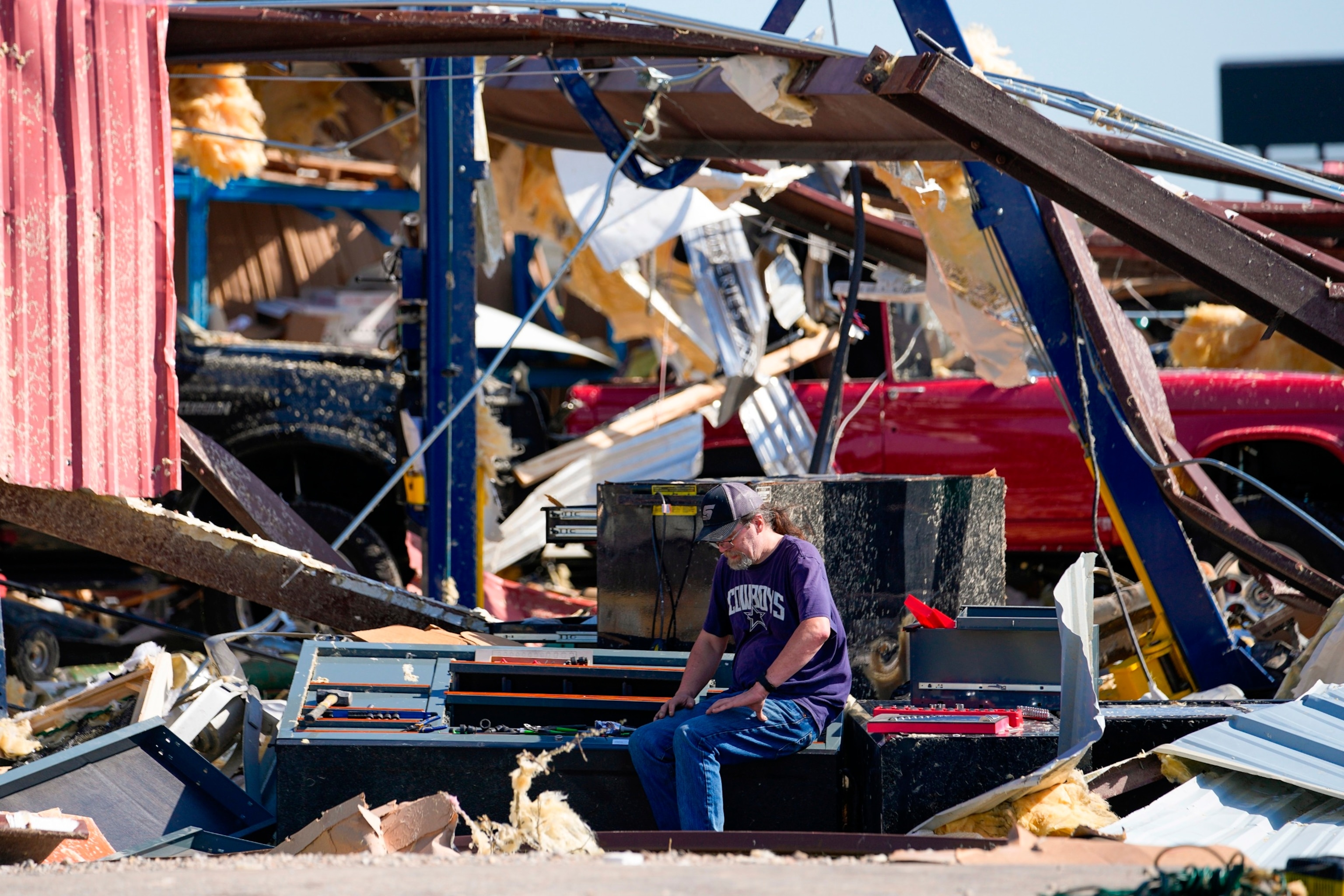 PHOTO: An employee of a body shop collects tools near damage the morning after a tornado hit, May 26, 2024, in Valley View, Texas. 