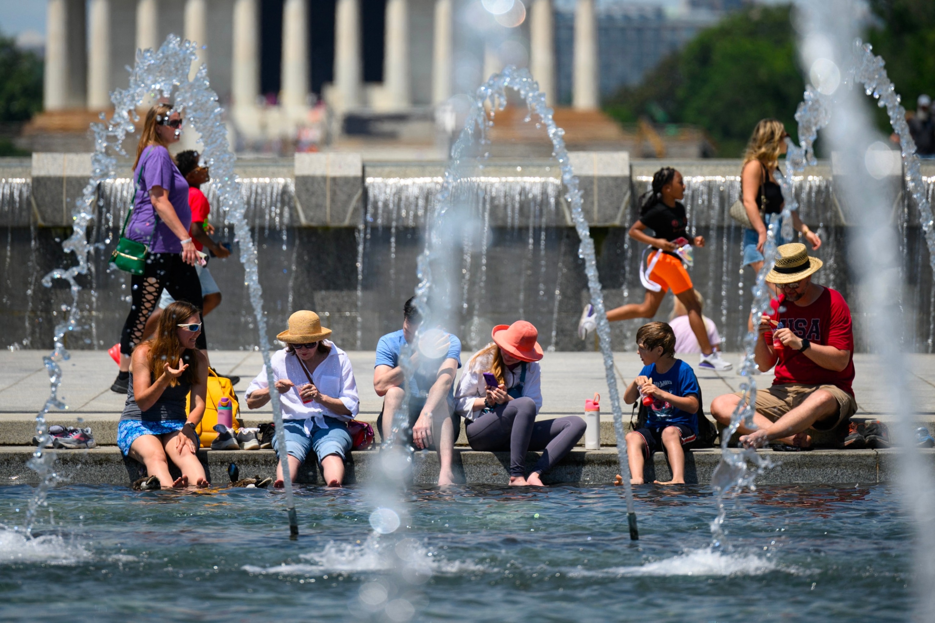 PHOTO: People put their feet in the water to cool off at the US World War II Memorial in Washington, DC, June 19, 2024. 
