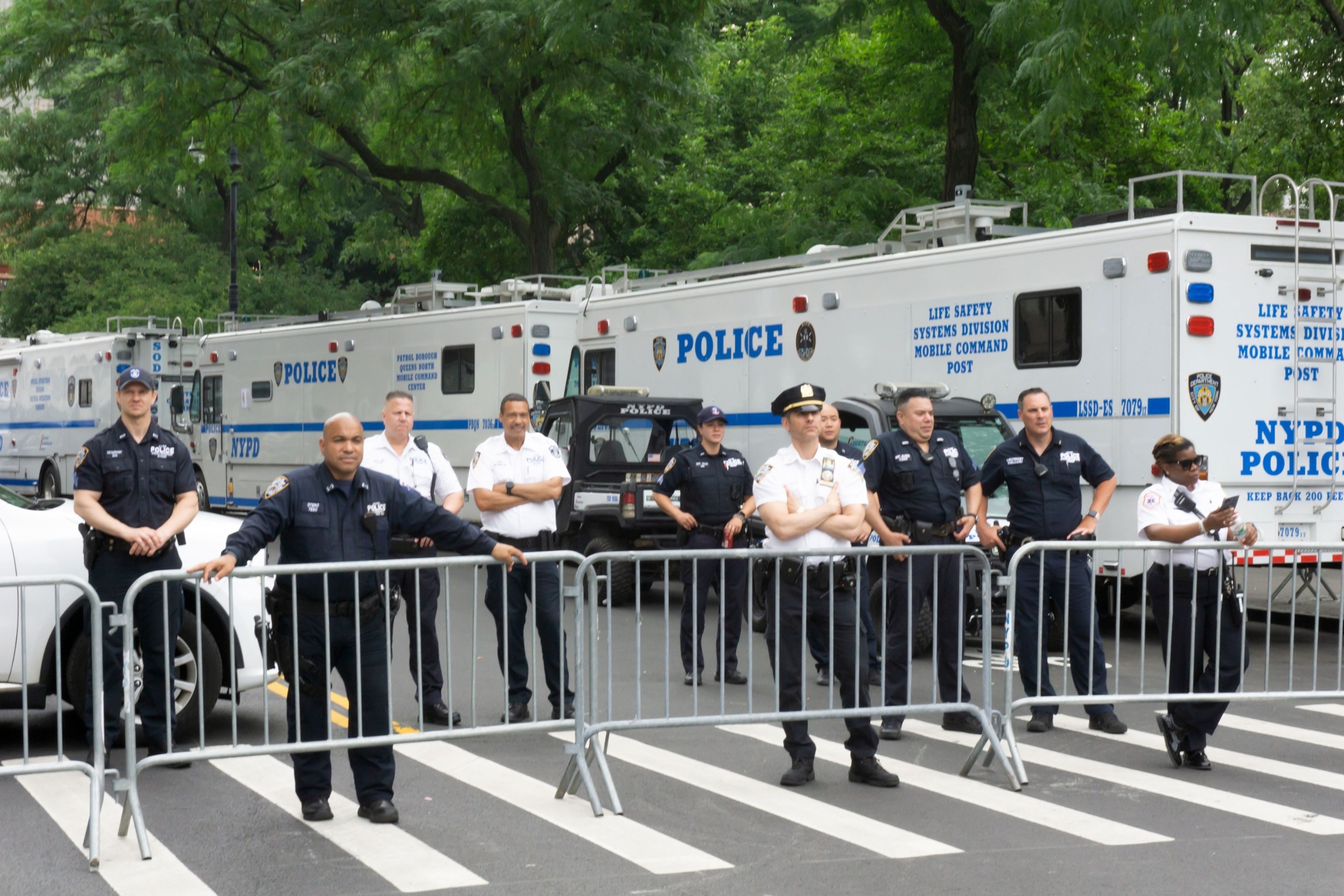 PHOTO: In this June 25, 2023, file photo, New York City Police Department officers, standing behind a bicycle rack barricade and in front of 3 large NYPD Mobile Command Post vehicles, monitor the NYC Pride March 2023, near Christopher Street in New York.
