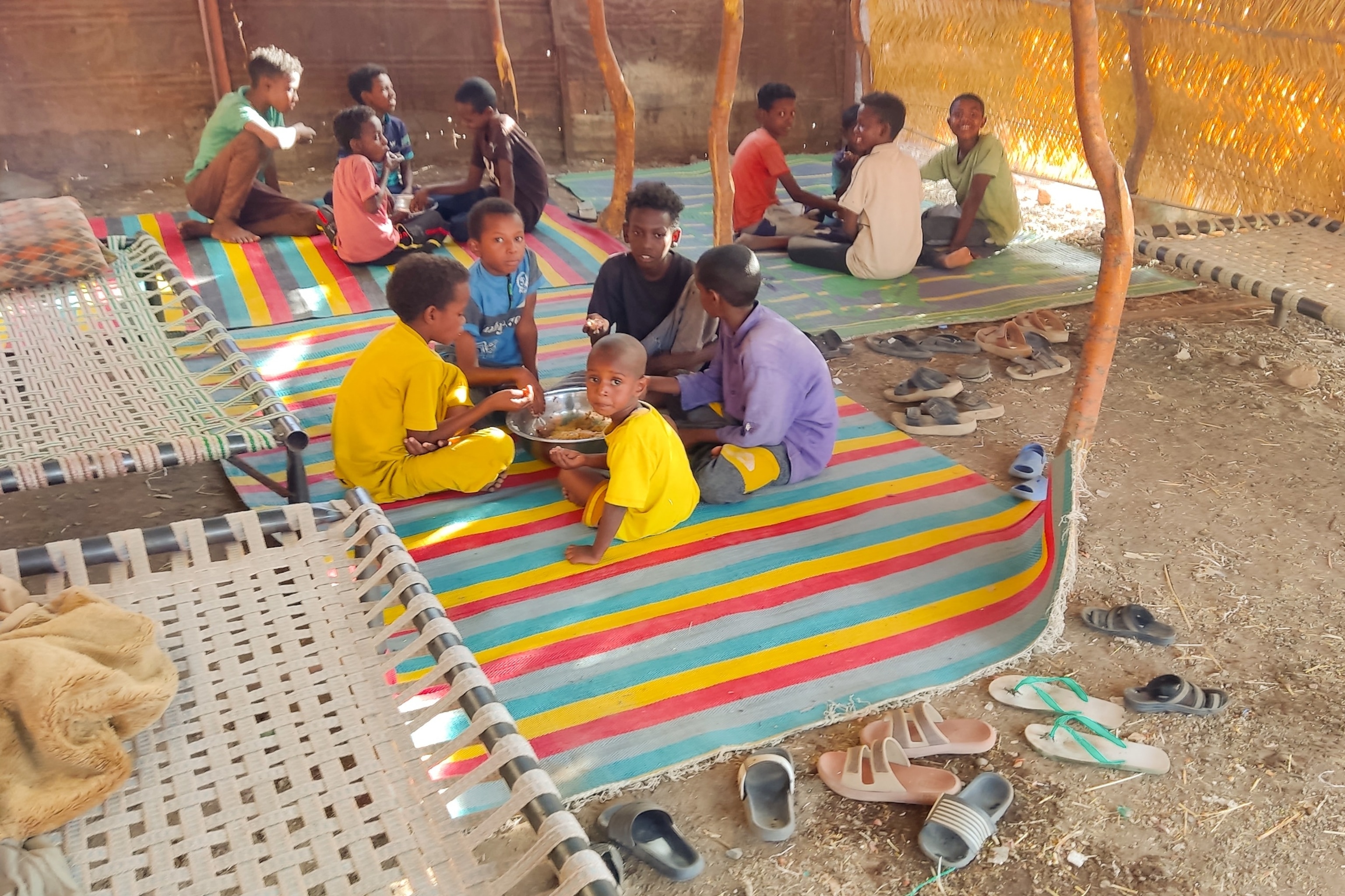 PHOTO: Children sit together sharing a large bowl of food, as Sudanese families host internally displaced people coming from the central Sudanese state of Gezira to the eastern Sudanese city of Gedaref on June 3, 2024. 