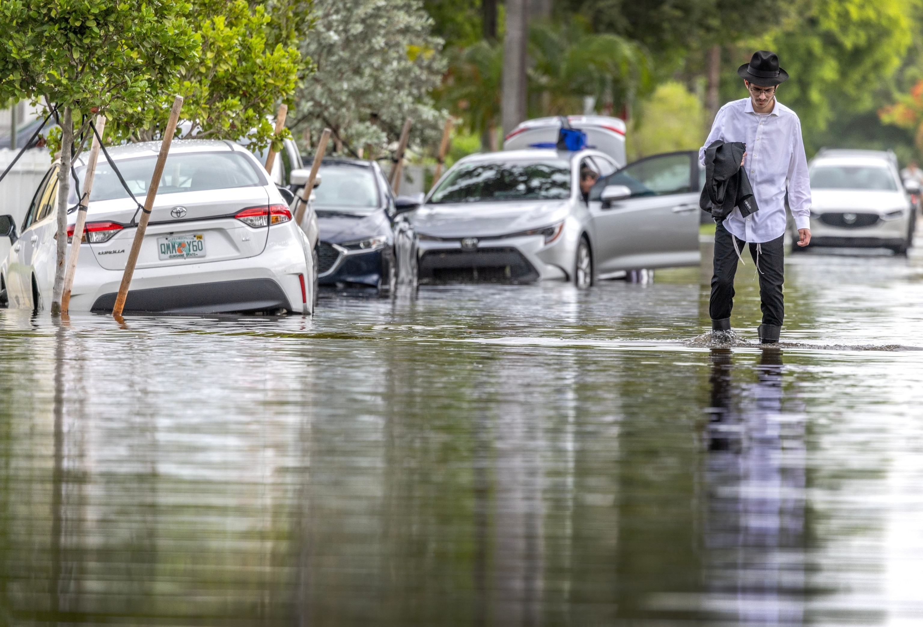 PHOTO: A person walks next to stuck cars, in a flooded neighborhood in Hallandale Beach, Florida, June 13, 2024. 