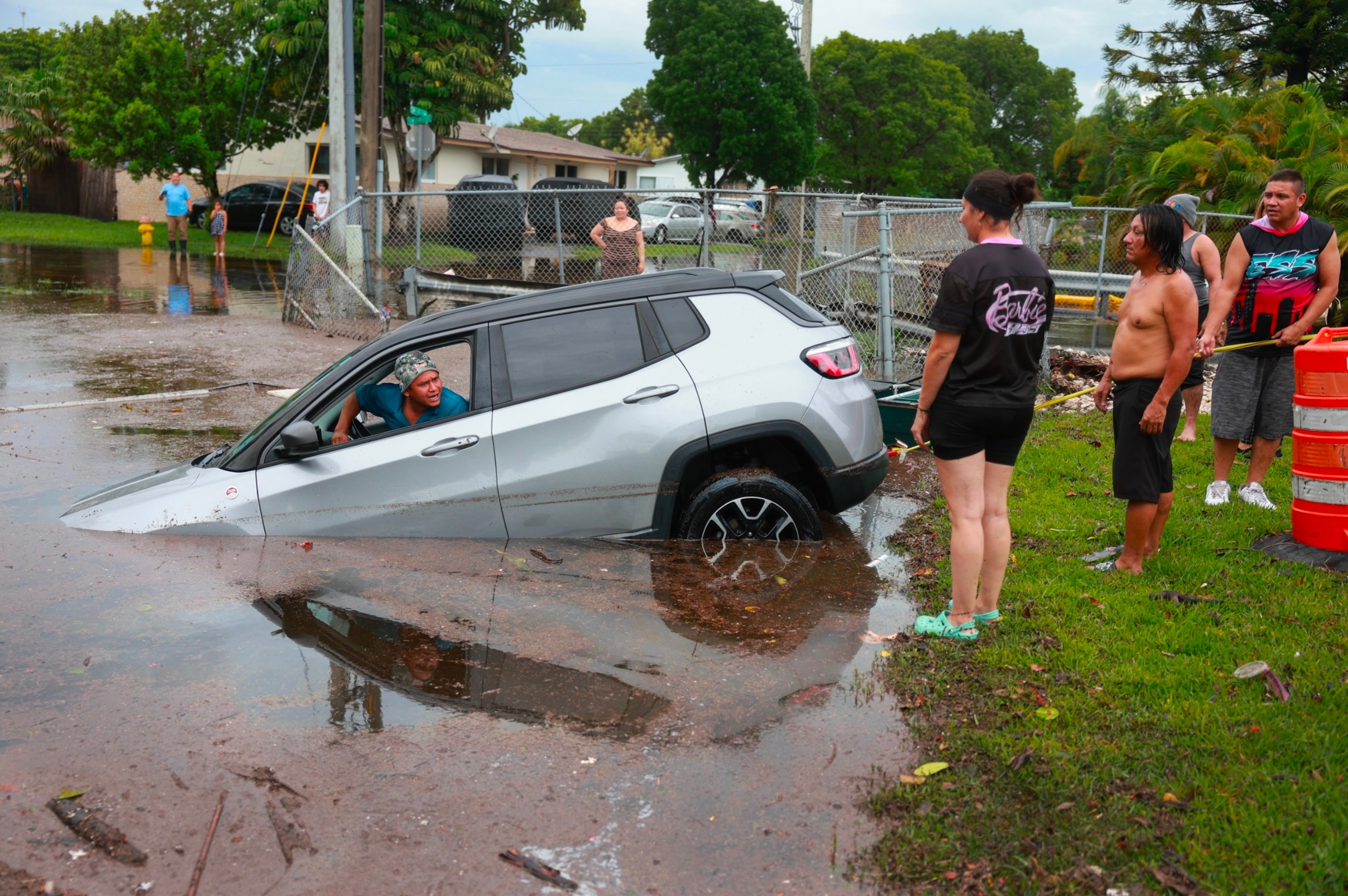 PHOTO: Oscar Trejo sits in a car after putting the vehicle into neutral as he helps attempt to pull it out of the canal on June 13, 2024, in Hallandale Beach, Florida.