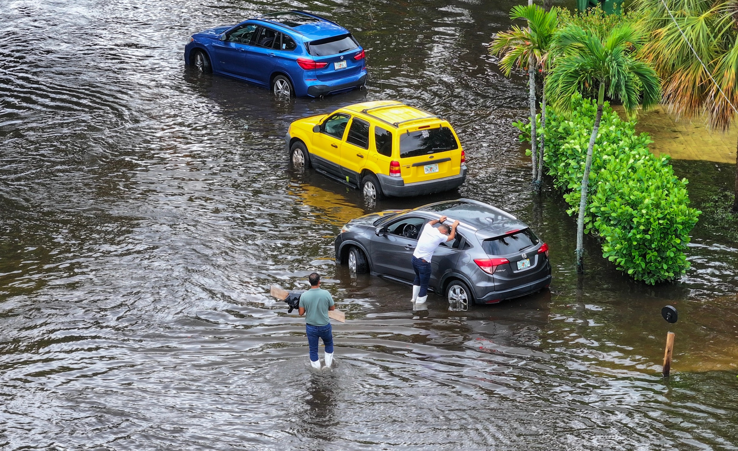 PHOTO: In an aerial view, people check on a car stuck in a flooded street on June 13, 2024, in Hallandale Beach, Florida. 