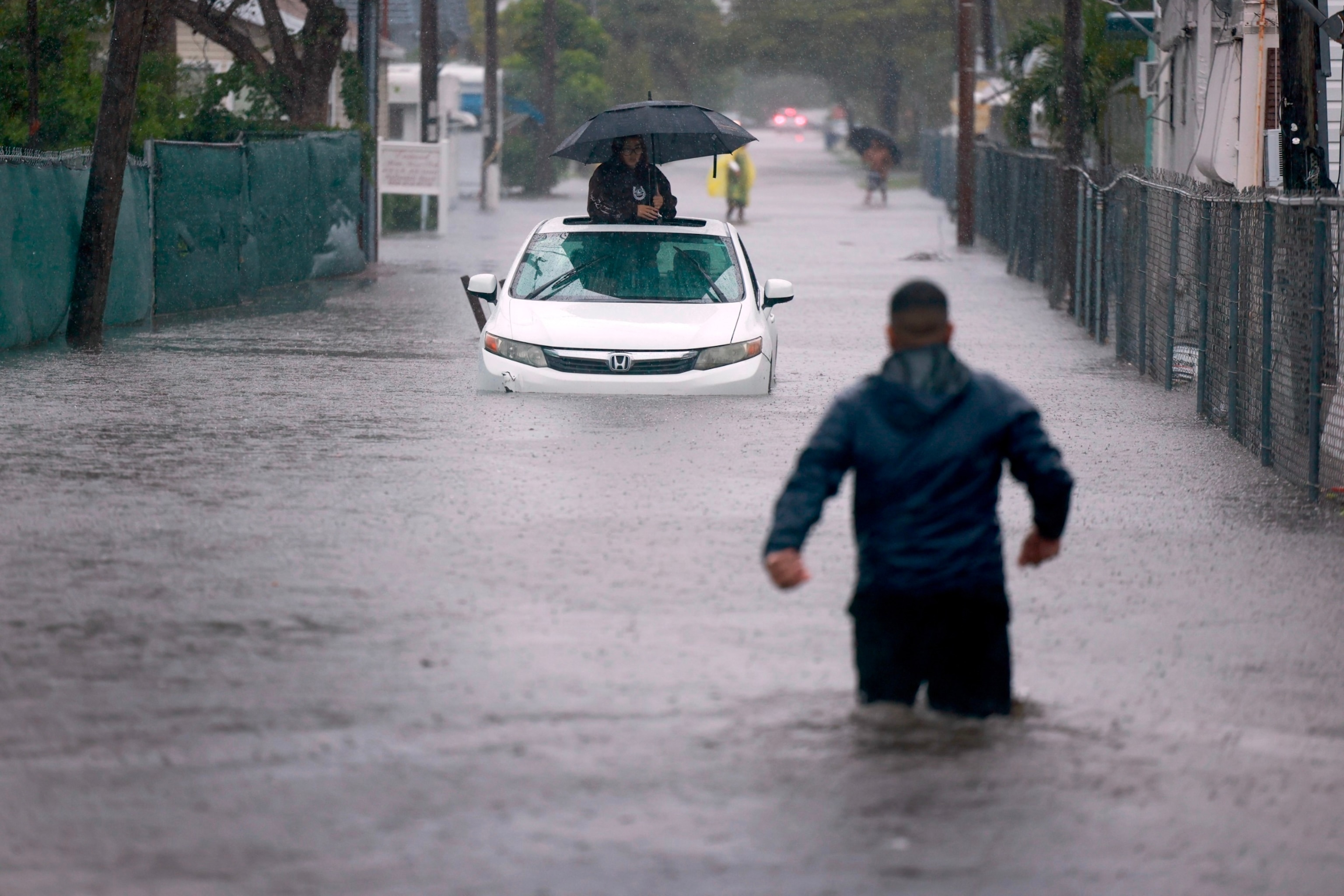 PHOTO: A person waits for help in a stalled vehicle sitting in the flooded street on June 12, 2024, in Hallandale Beach, Florida. 