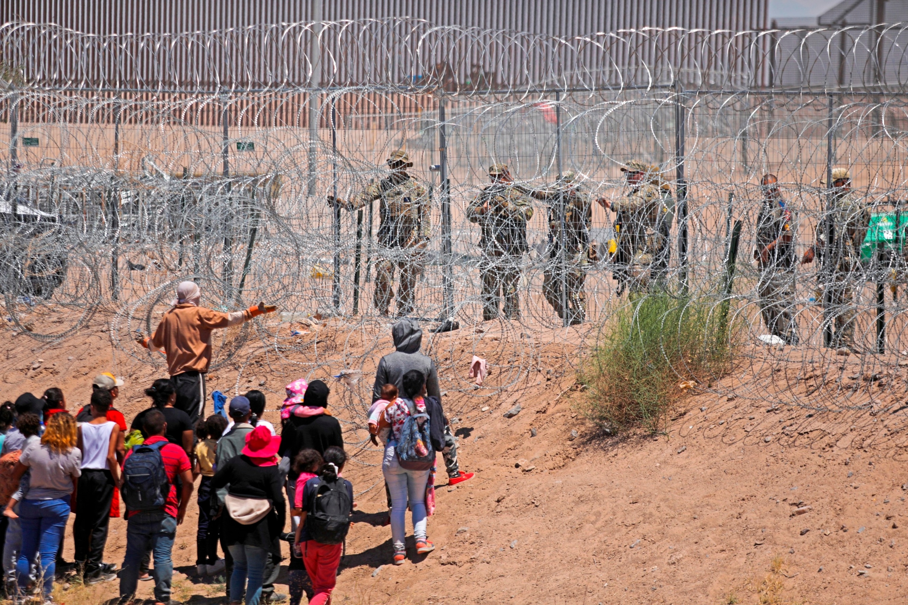 Migrants seeking to enter the United States through a barbed wire fence installed along the Rio Grande are driven away with pepper spray shots by Texas National Guard agents at the border with Ciudad Juarez, Chihuahua State, Mexico, on May 13, 2024. 