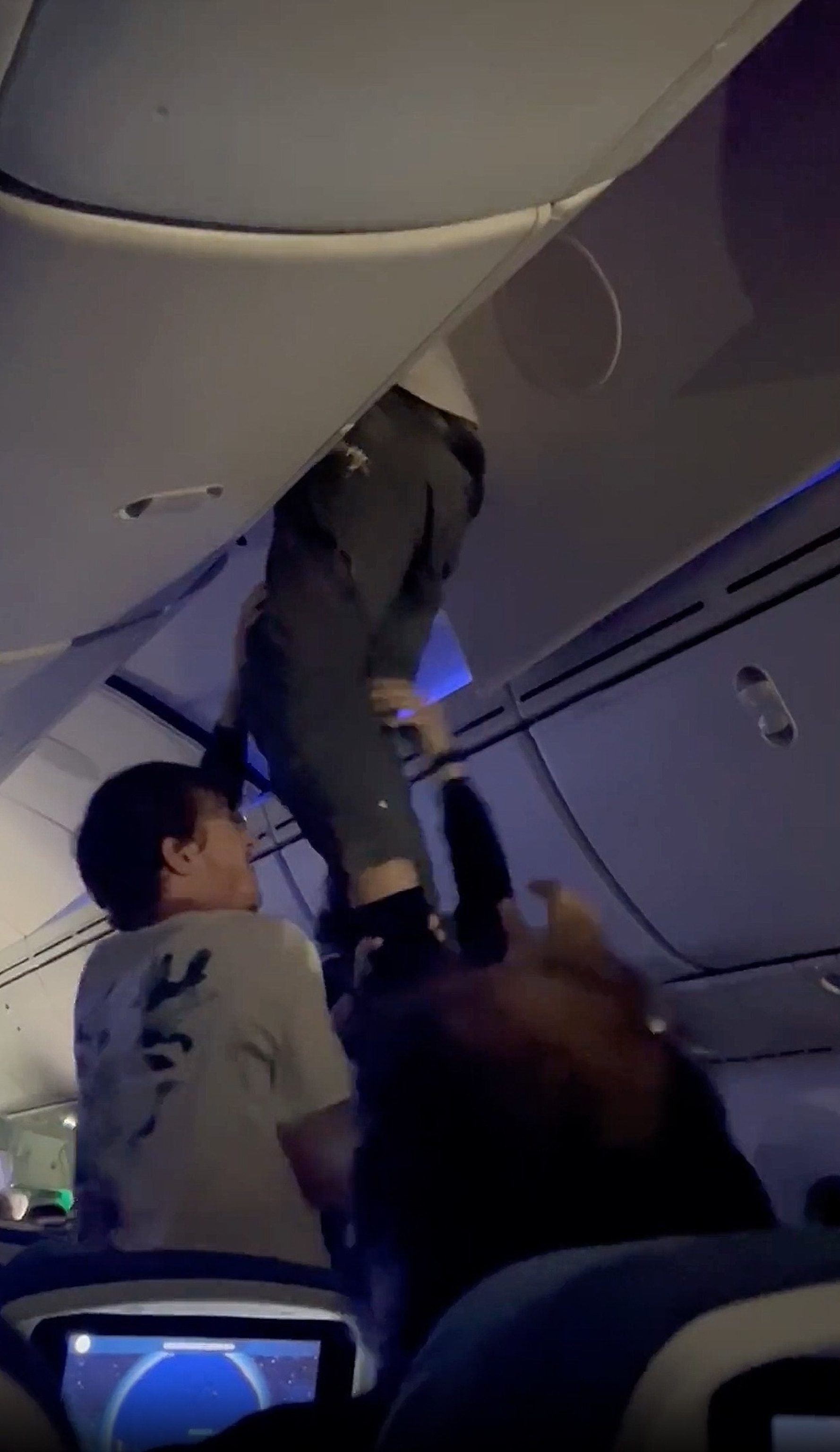 PHOTO: A man is seen dangling from the overheard compartment of an Air Europa following severe turbulence, July 1, 2024. It is unclear how he ended up there.