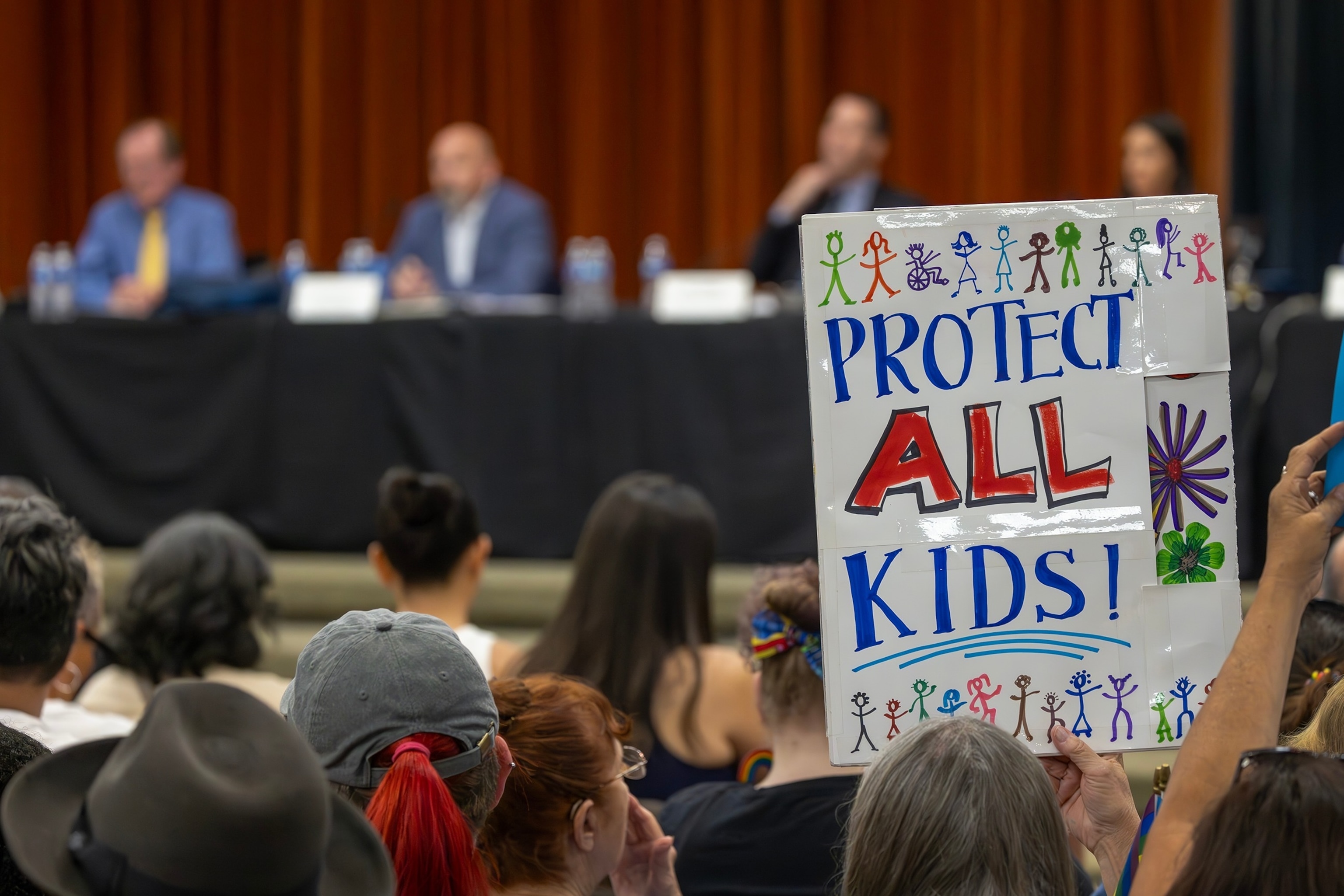 PHOTO: A person holds a sign in opposition to a policy that the Chino Valley school board is meeting to vote on, Chino, CA, July 20, 2023.