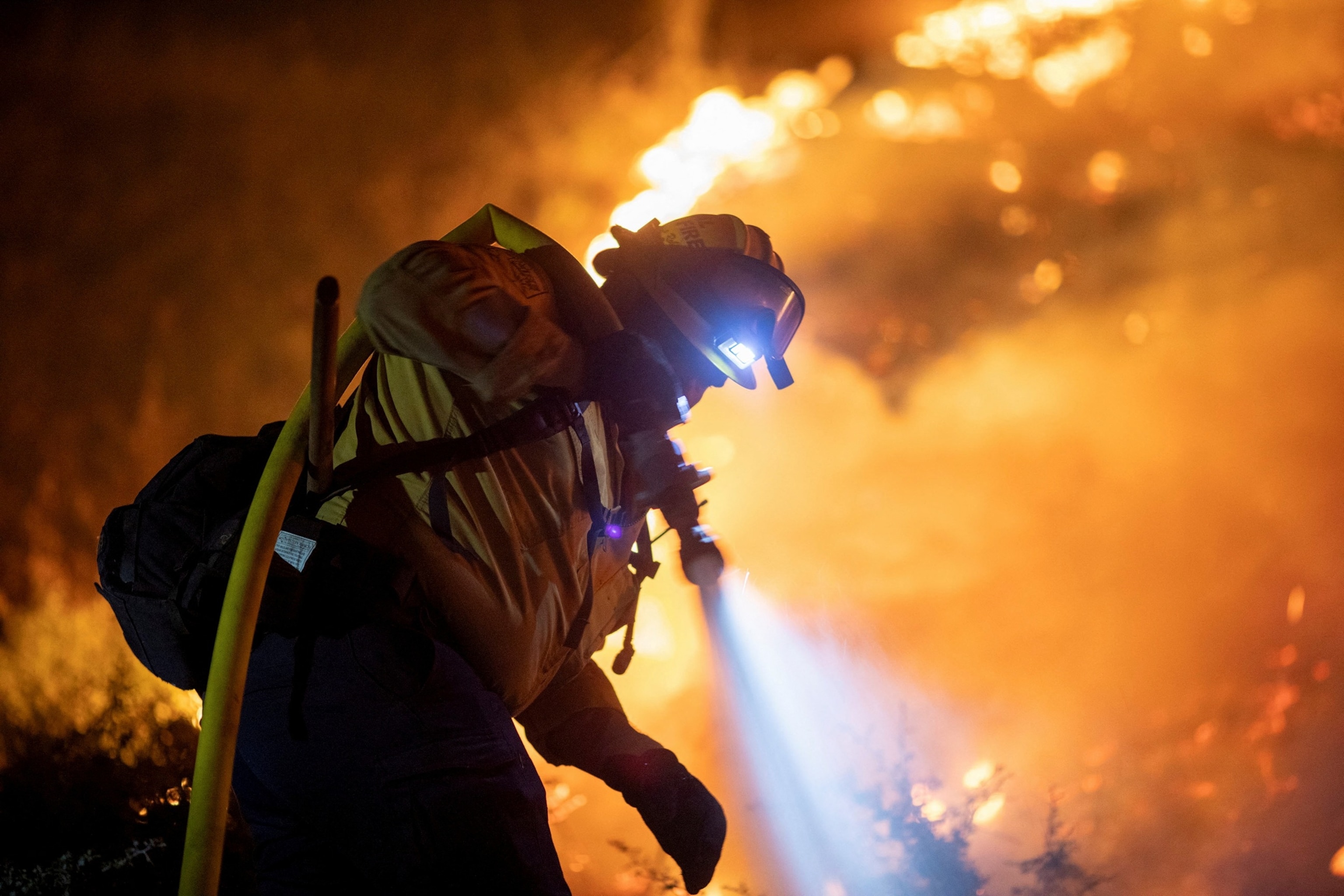 A Cal Fire firefighter tackles the Bridge Fire threatening mountain communities to the northeast of Los Angeles, in Wrightwood, California, U.S. September 11, 2024.  REUTERS/Ringo Chiu